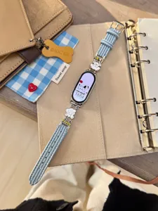 Detailansicht des stilvollen blauen Denim-Smartwatch-Armbands mit süßen Welpen-Metallanhängern.