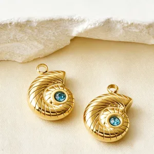 Gros plan détail de pendentifs coquillage dorés avec cristal bleu pour accessoires de bijoux.