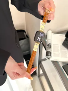 Nahaufnahme des braunen Lederarmbands mit goldenen Kleeblatt-Anhängern für Smartwatch.