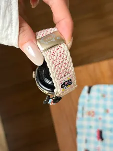 Vue détaillée du bracelet de montre en nylon tressé avec pendentif chat et boucle.