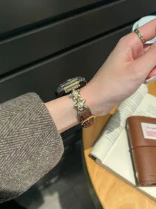 Détail de bracelet de montre en velours côtelé perle étoile avec breloques métalliques.