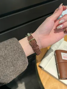 Gros plan détaillé du bracelet de montre Apple en velours côtelé marron avec pendentif.