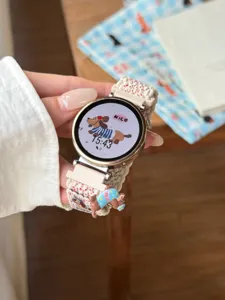Vue détaillée du bracelet de montre de rechange en nylon tissé beige avec charm chien.