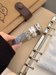 Detailansicht des grauen Denim-Smartwatch-Armbands mit süßen Welpen-Metallanhängern.