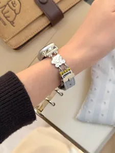 Detailansicht des grauen Jeans-Leder-Smartwatch-Armbands mit süßem Welpen-Metallketten-Anhänger.