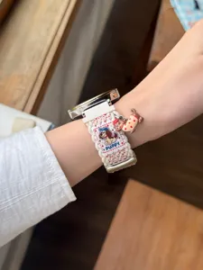 Gros plan détaillé du bracelet de montre en nylon tressé avec broderie de chiot et charm.