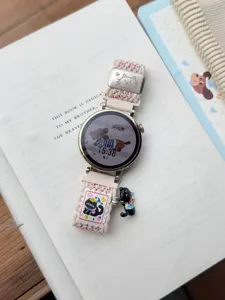 Gros plan détaillé du bracelet de montre en nylon tissé avec boucle et charm chat mignons.