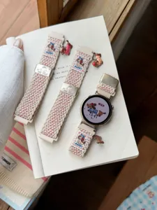 Détail de bracelet de montre en nylon tressé avec charmant chiot et boucle métal.