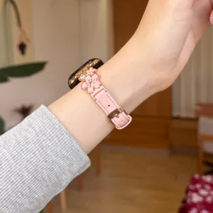 Close-up of pink leather watch strap with metal flower charms, perfect detail view.
