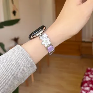 Detailed close-up of the elegant metal flower and purple leather watch strap worn gracefully on wrist.
