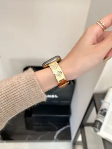 Nahaufnahme des Metall-Leder Apple Watch Armbands mit glitzerndem Strass-Kleeblatt am Handgelenk.