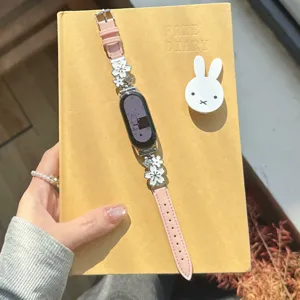 Detailed view of pink leather smartwatch strap decorated with elegant metal flower charms.