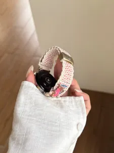 Détail de bracelet de montre en nylon tressé, charm chiot mignon et boucle métal pour smartwatch.