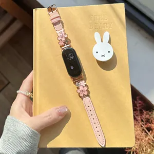 Close-up of pink leather watch strap featuring metal cherry blossom charms. Elegant and sweet.