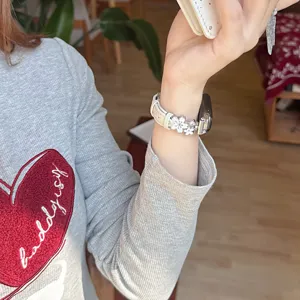 Metal flower leather watch band compatible with Apple Watch, elegant white strap replacement.