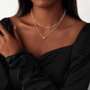 Dettaglio collana doppia strato dorata raffinata con pendente in zircone brillante ed elegante.