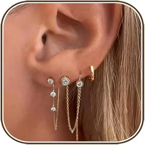 Close-up detail of multi-piece layered zirconia chain stud earrings and small gold hoop set.