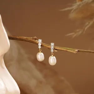 Detailopname van prachtige 14k vergulde oorbellen met sprankelende zirkoon en elegante parel.