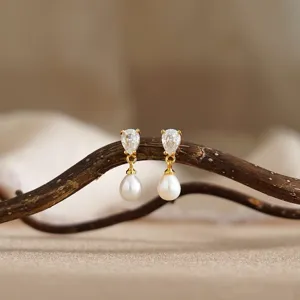 Elegante oorbellen met sprankelende zirkoon en glanzende parels op tak gepresenteerd.