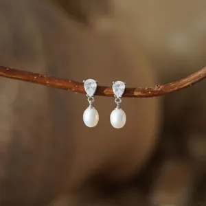 Detailopname van druppel zirkonia en parel oorbellen, elegant en stralend sieraad detail.