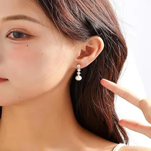 Primo piano dettagliato di eleganti orecchini placcati oro 14k con zirconi e perla.