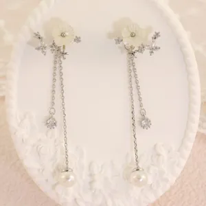 Primo piano dettagliato di orecchini lunghi con perle, fiori di conchiglia e zirconi brillanti.