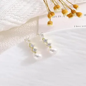 Primo piano di orecchini pendenti placcati in oro 14k con zirconi cubici e perle molto eleganti.