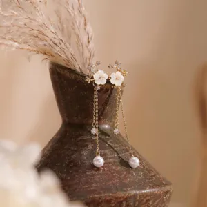 Primo piano dettagliato di lunghi orecchini di perle floreali con zirconi scintillanti.