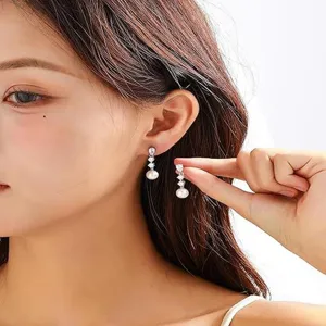 Primo piano dettagliato di eleganti orecchini pendenti con zirconi brillanti e perla.