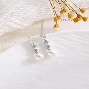Squisito scatto di dettaglio di orecchini pendenti in zircone e perla dal design elegante.