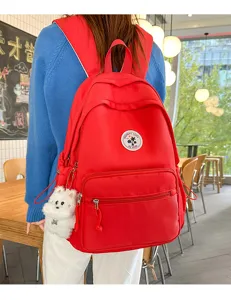 Vista dettagliata di uno zaino casual rosso tinta unita elegante con grazioso ciondolo in peluche.