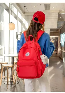 Zaino casual minimalista rosso in dettaglio con tasca frontale e ciondolo soffice.