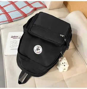 Vista dettagliata dello zaino casual nero con toppa logo e ciondolo di peluche.