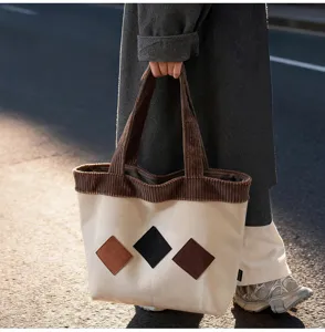 Close-up detail of casual canvas tote bag with brown corduroy trim and stylish diamond patches.