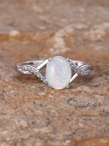 Close-up detail of the elegant cross-twisted opal ring, featuring shimmering paved stones.