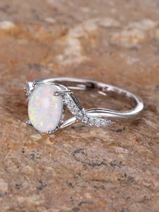 Elegant oval white opal ring with sparkling paved diamonds on a crossed twisted band design.