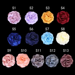 Close-up details of multi-color fabric camellia flower brooches showing various color options.