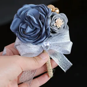 Elegant wedding boutonniere with blue fabric roses, silver ribbon bow and crystal heart.