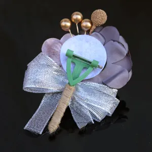Detailed view of handmade fabric wedding boutonniere back with silver ribbon and pin.