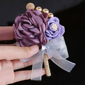 Close-up detail of purple fabric rose wedding boutonniere with crystal bow and gold beads.
