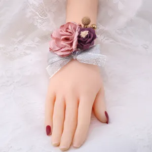 Korean style wedding wrist corsage with pink and purple fabric flowers and silver bow accessory.