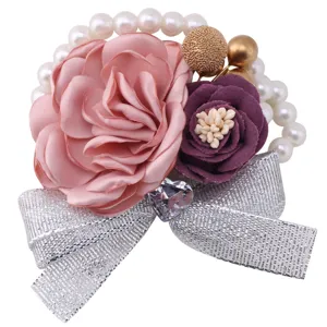 Detailed close-up view of wedding wrist corsage featuring pink rose and silver glitter bow.