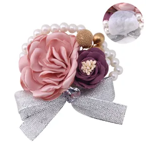 Close-up detail of wedding corsage featuring pink rose, pearls, and silver glitter bow.