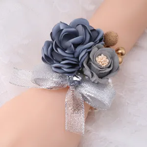 Detailed close-up of artificial rose wrist flower with silver ribbon and crystal decor.
