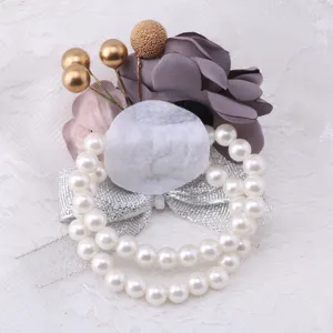 Elegant wedding wrist corsage with artificial flowers pearls and silver bow for bridal party.