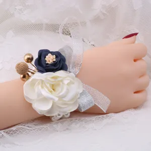 Detailed close-up of wedding wrist corsage with floral design and silver mesh ribbon decor.