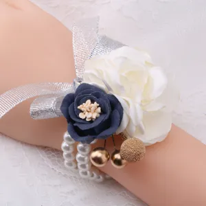 Artificial flower wrist corsage detail view, featuring white and navy blue roses with pearl bracelet.