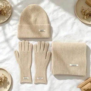 Detailansicht eines dreiteiligen Wintersets aus beige Strickmütze, Handschuhen und Schal.