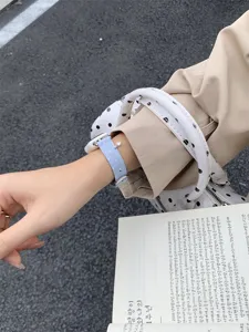 Vista dettagliata di un cinturino per smartwatch in maglia a pois con ciondolo.