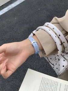 Dettaglio cinturino orologio in tessuto a pois azzurro, consistenza morbida e accessorio.